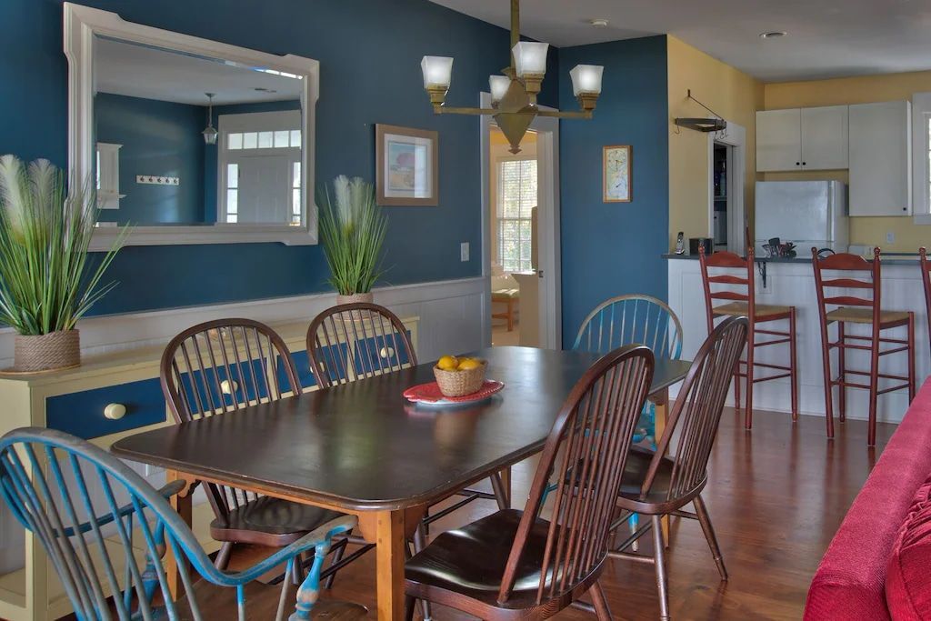 A dining room with a table and chairs and a mirror