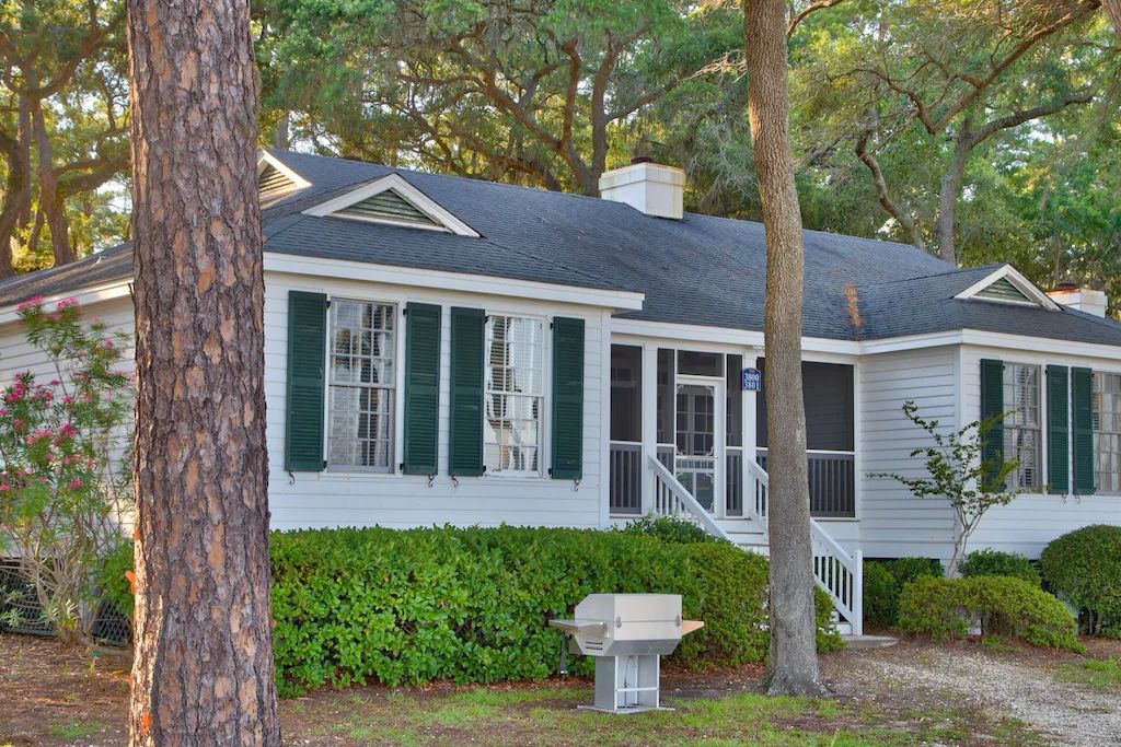 A white house with a black roof and green shutters
