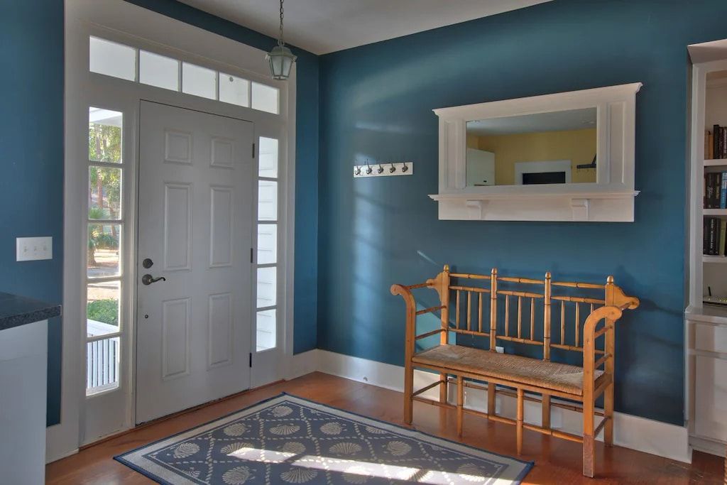 A hallway with blue walls and a bench and a mirror