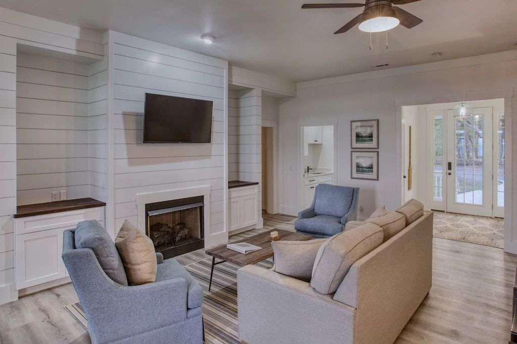 A living room with a couch , chairs , fireplace and television.