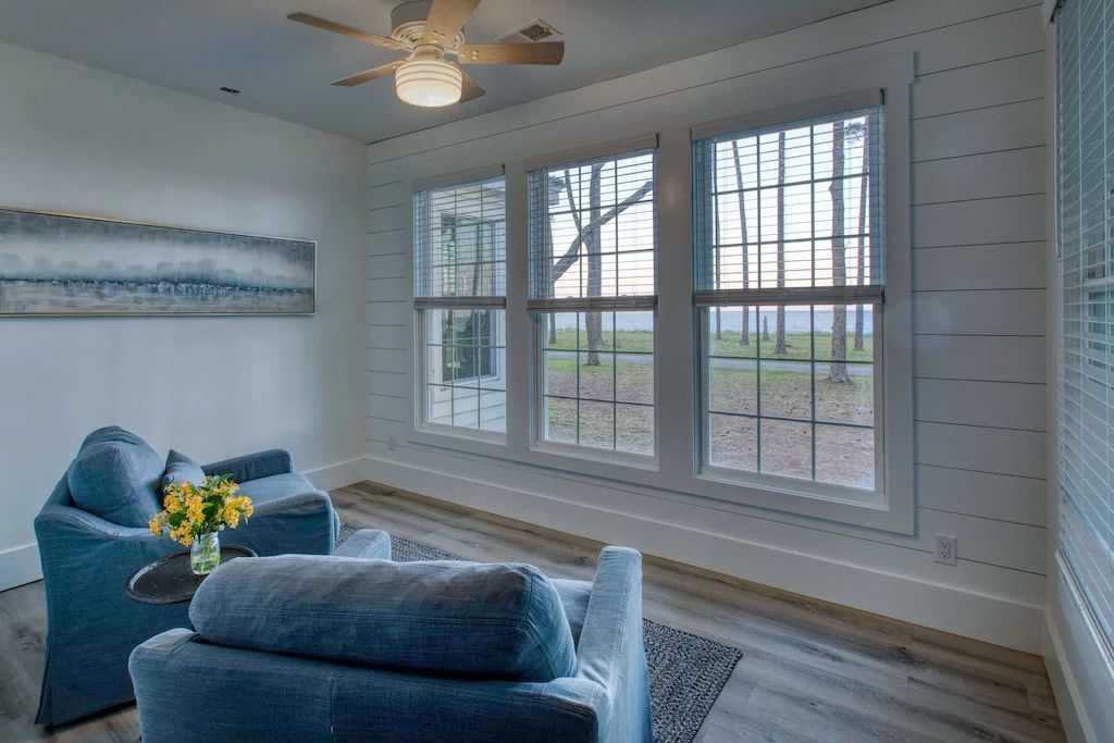 A living room with a lot of windows and a ceiling fan.