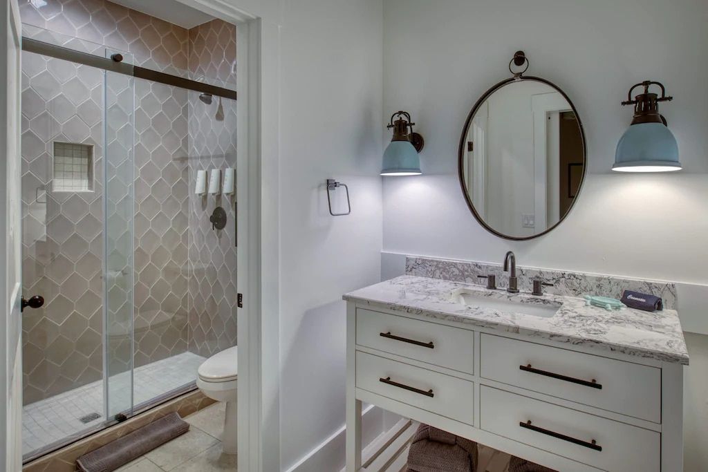 A bathroom with a sink , toilet , shower and mirror.