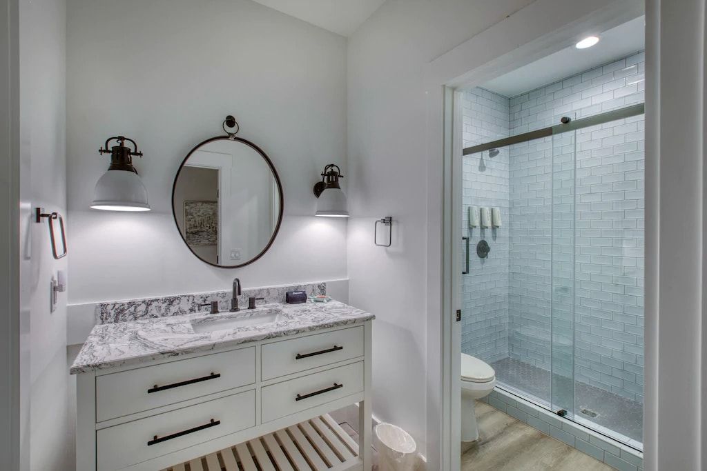 A bathroom with a sink , mirror , toilet and shower.