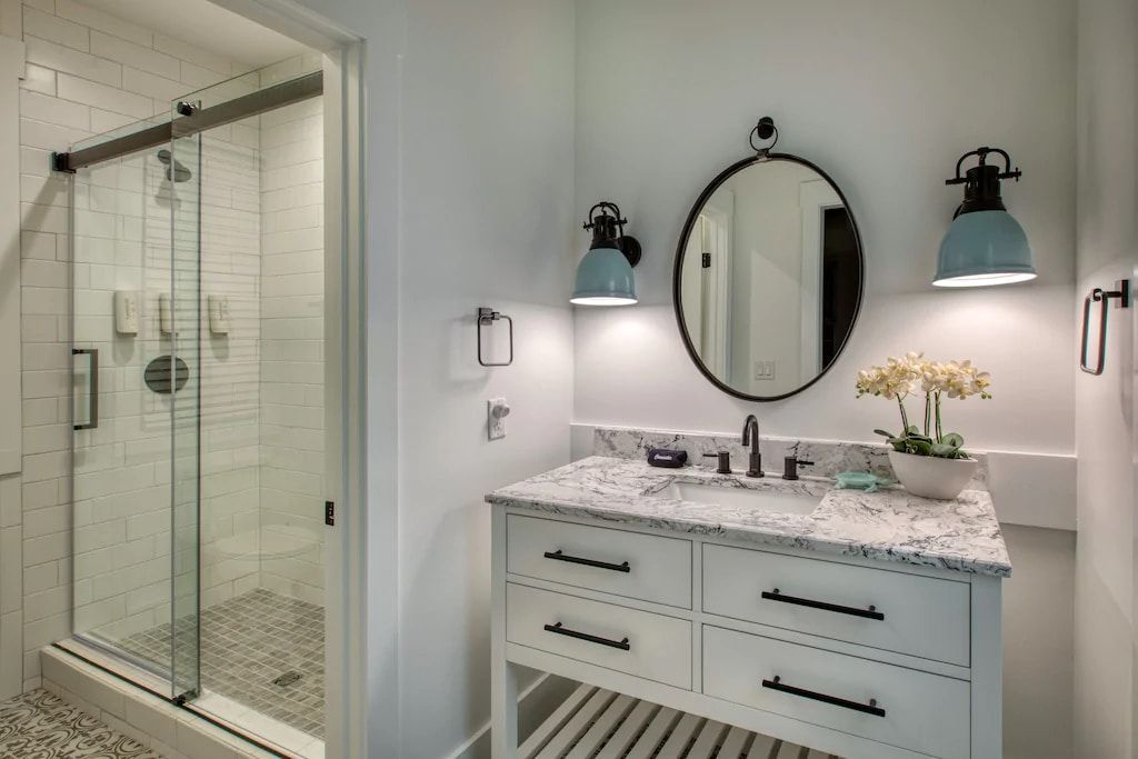 A bathroom with a sink , mirror and shower.