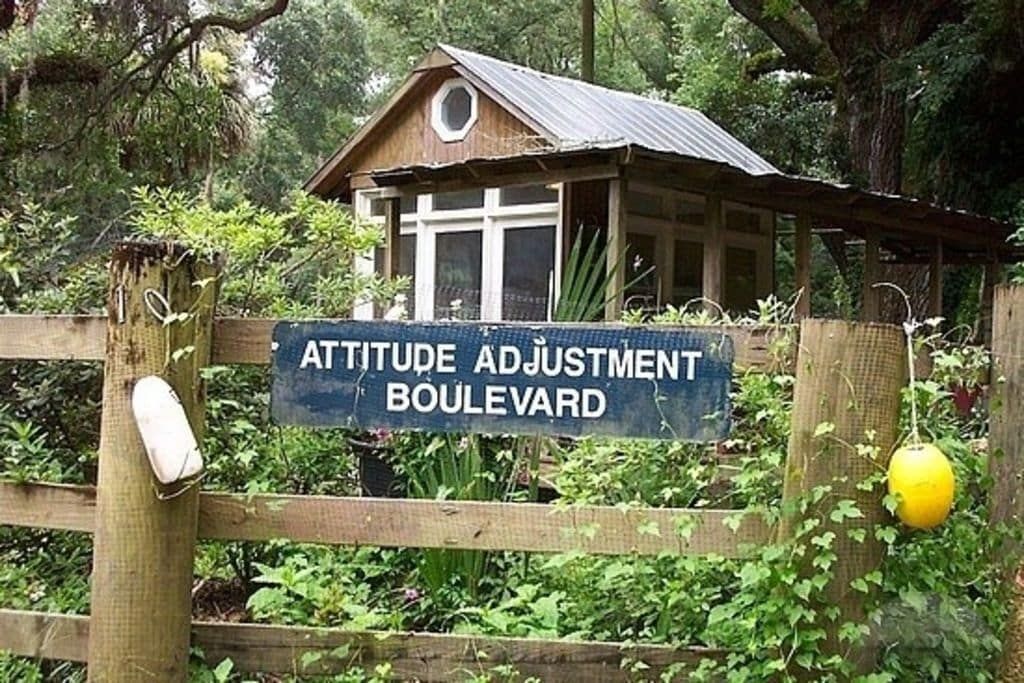 A wooden fence with a sign that says attitude adjustment boulevard