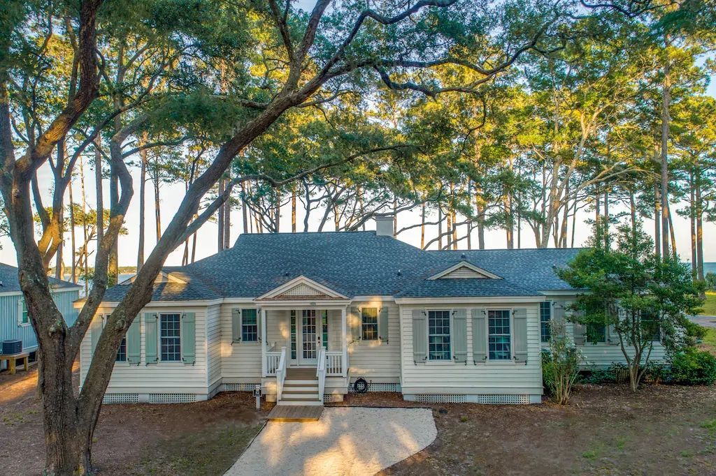 A large white house with a blue roof is surrounded by trees.