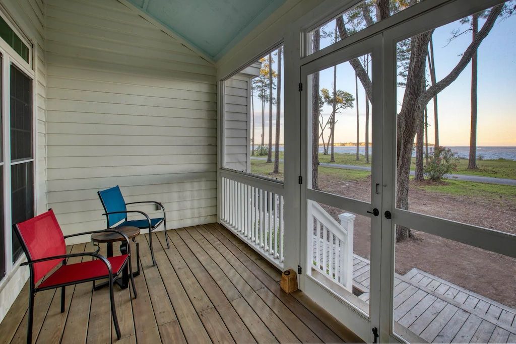 A screened in porch with two chairs and a table