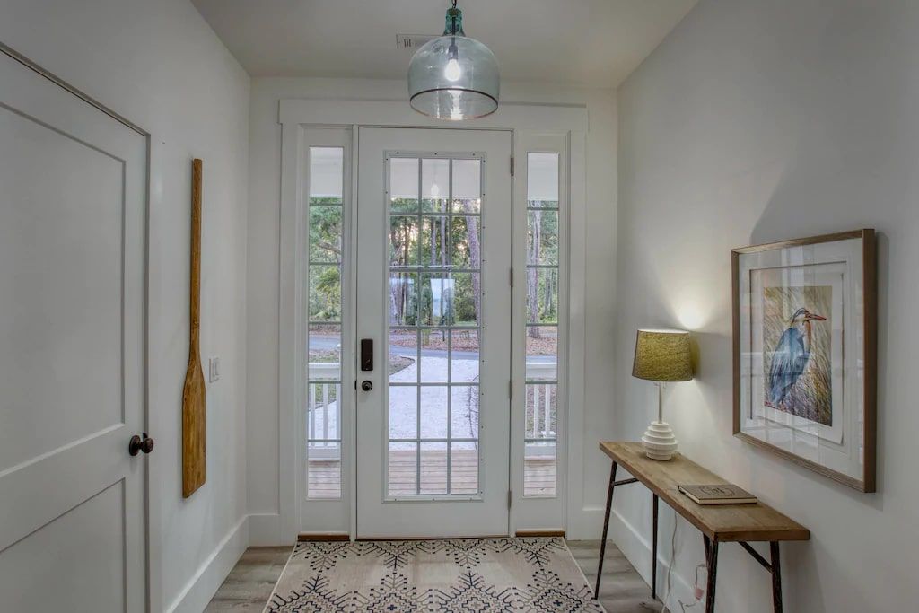 A hallway with a table and a lamp in front of a door.