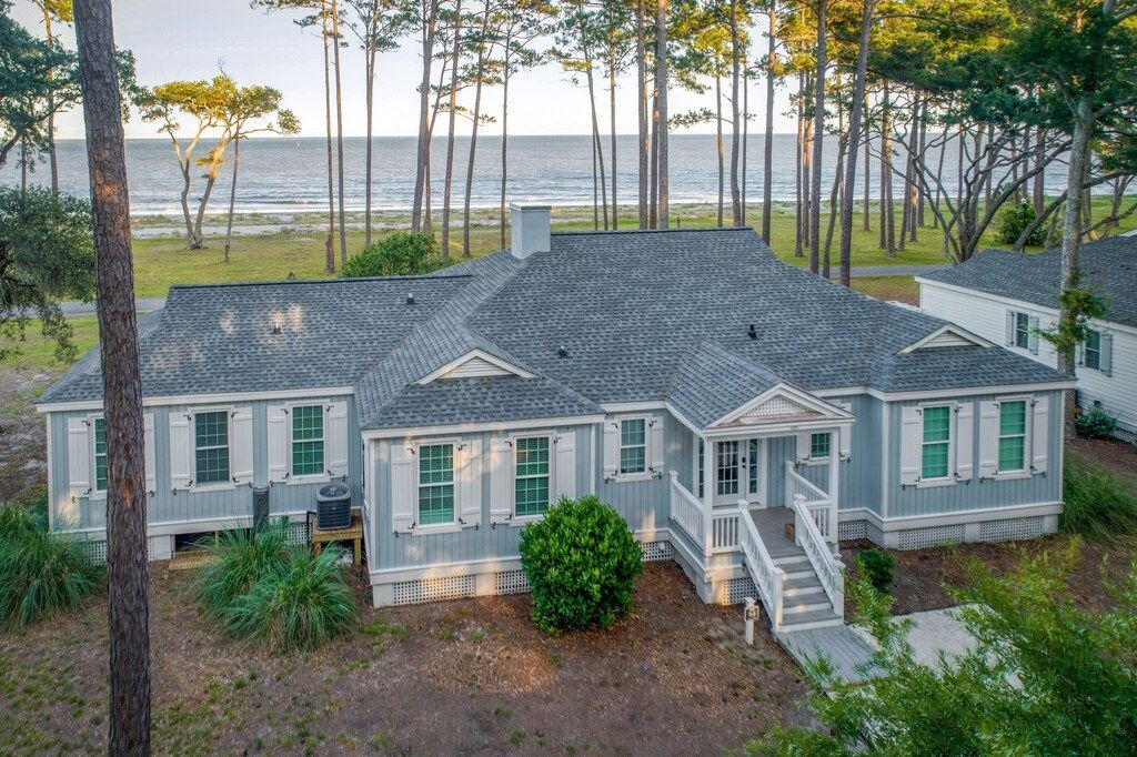 An aerial view of a large house surrounded by trees with a view of the ocean.
