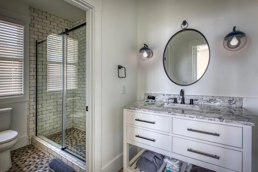 A bathroom with a sink , toilet , shower and mirror.
