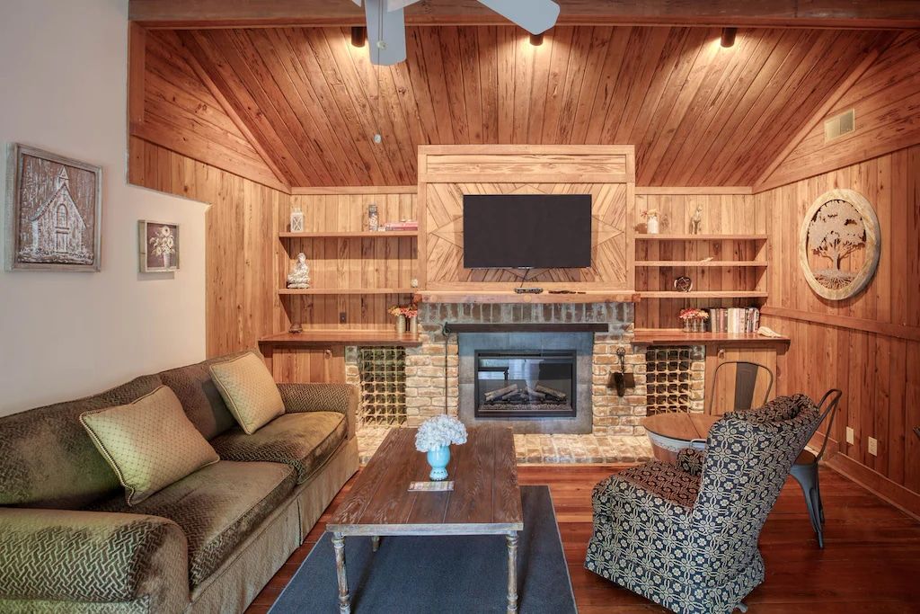 A living room with a couch , chair , coffee table , fireplace and television.