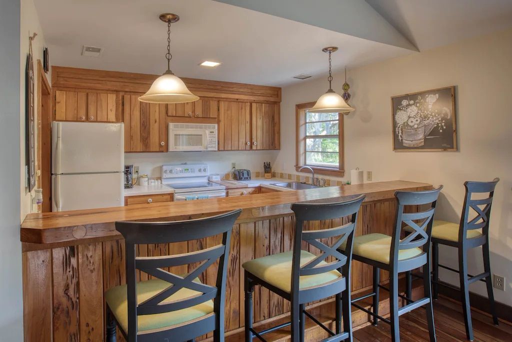 A kitchen with a bar and chairs and a refrigerator.