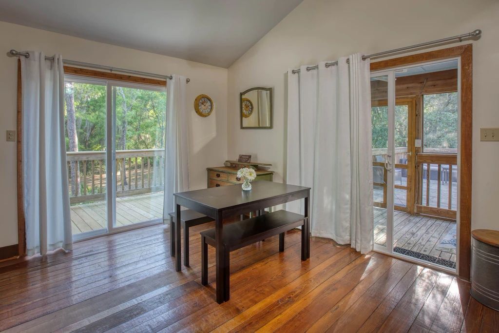 A dining room with a table and bench and sliding glass doors leading to a deck.
