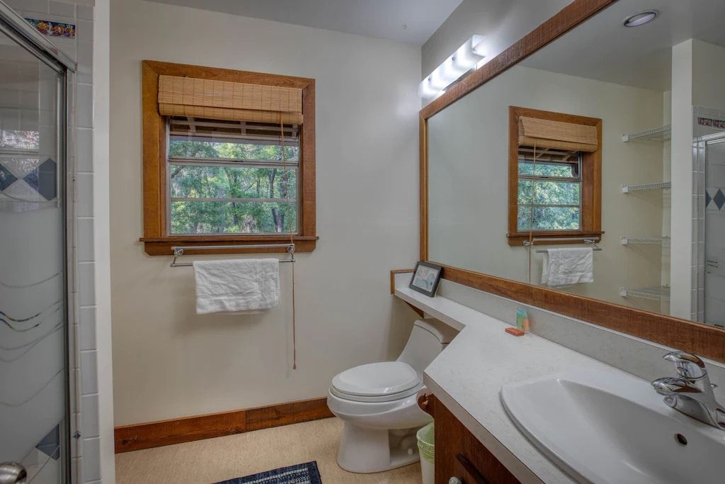 A bathroom with a toilet , sink , and mirror.