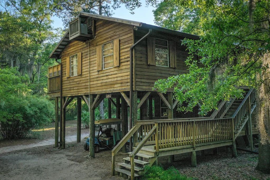 A wooden house on stilts with a golf cart parked in front of it.