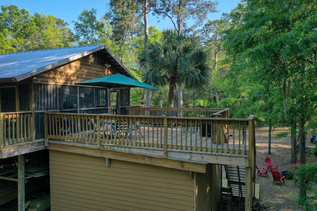 An aerial view of a house with a large deck surrounded by trees.