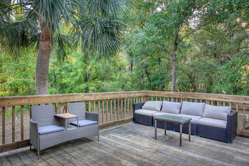 A wooden deck with a couch , chairs , and a table.