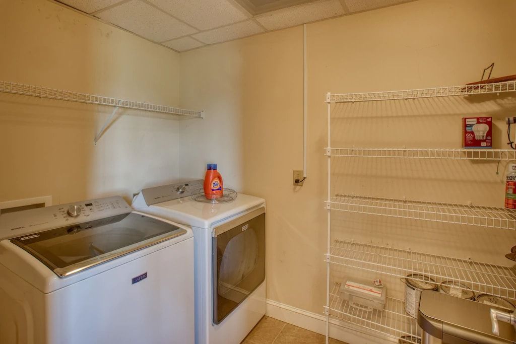 A laundry room with a washer and dryer and a wire rack.