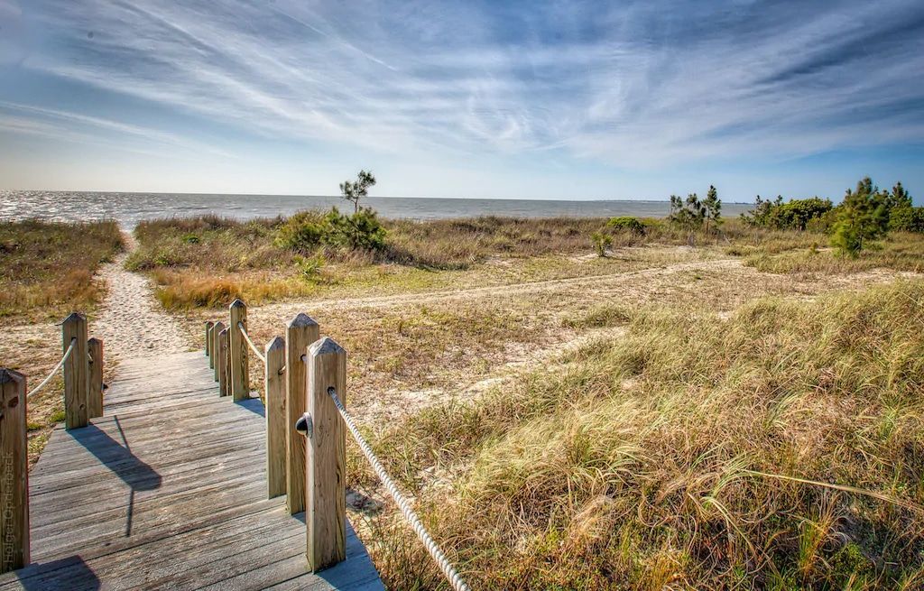 A wooden walkway leading to the beach on a sunny day.