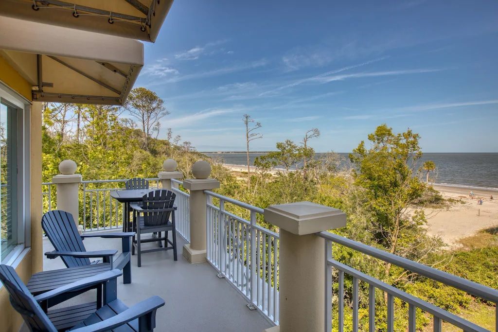 A balcony with chairs and a table overlooking the ocean.
