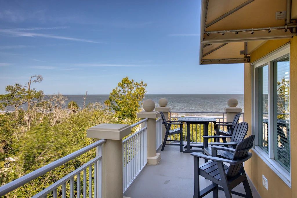 A balcony with chairs and a table overlooking the ocean