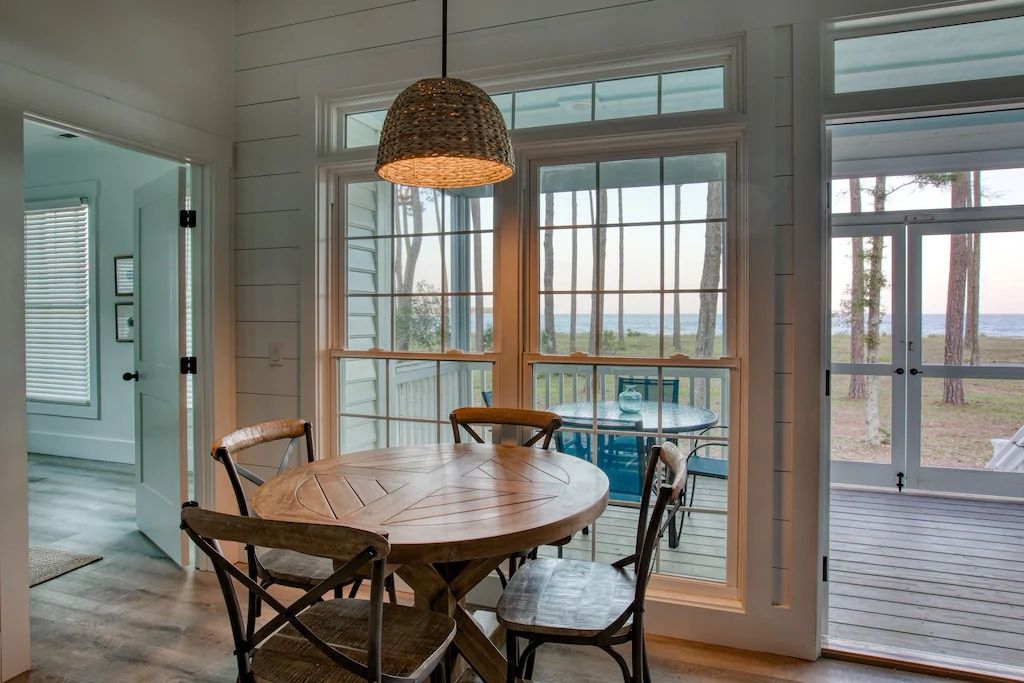 A dining room with a table and chairs and a large window.