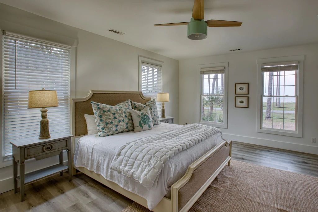 There is a ceiling fan in the bedroom with a large bed.
