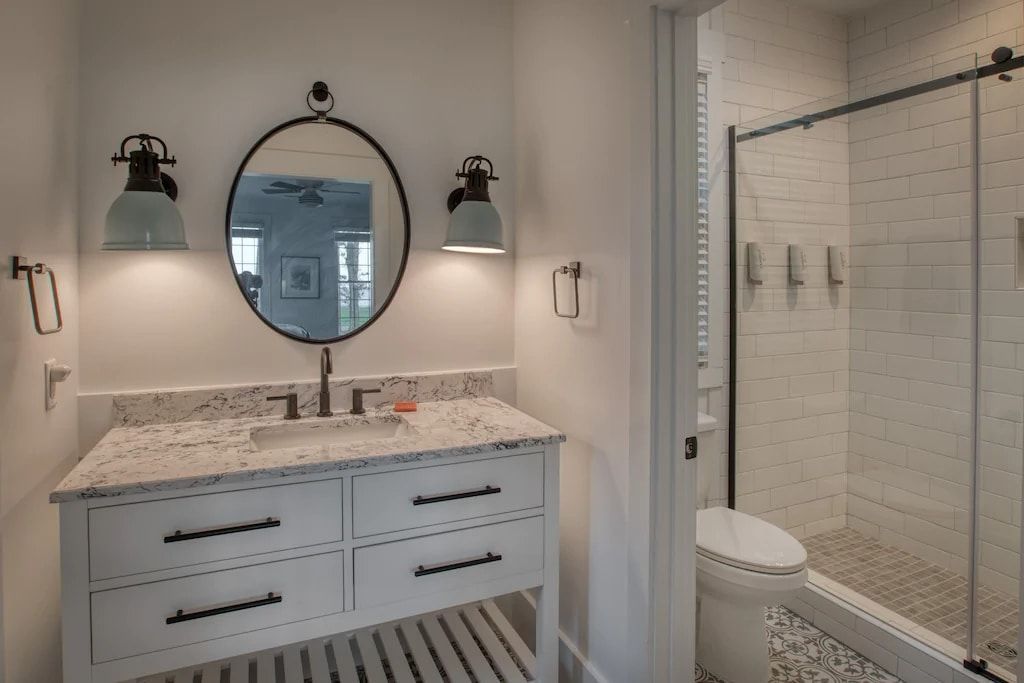 A bathroom with a sink , toilet , shower and mirror.