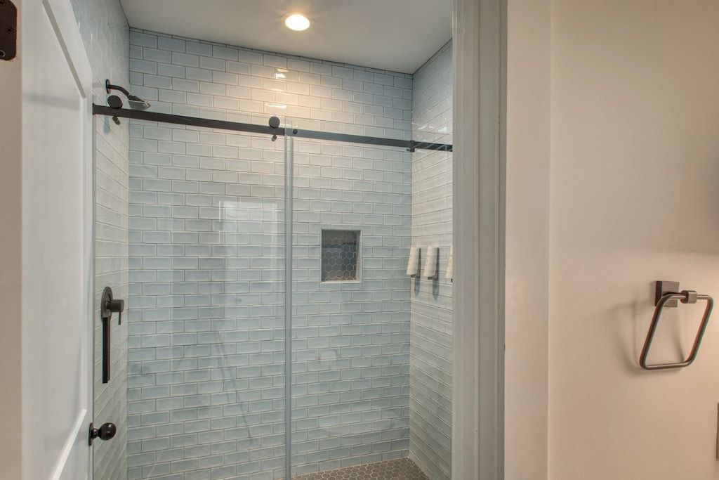 A bathroom with a walk in shower with a sliding glass door.