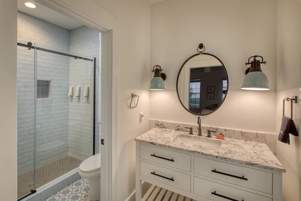 A bathroom with a sink , toilet , shower and mirror.