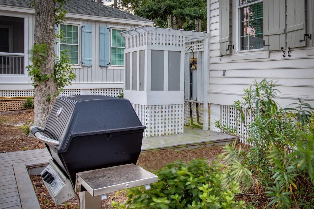 A grill is sitting in front of a white house.