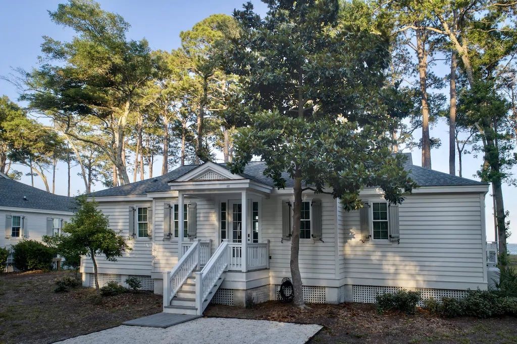 A white house is surrounded by trees and a gravel driveway