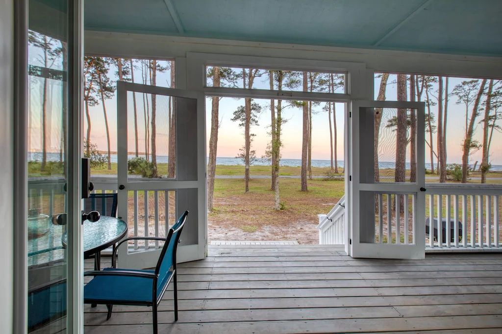 A screened in porch with a view of trees and the ocean