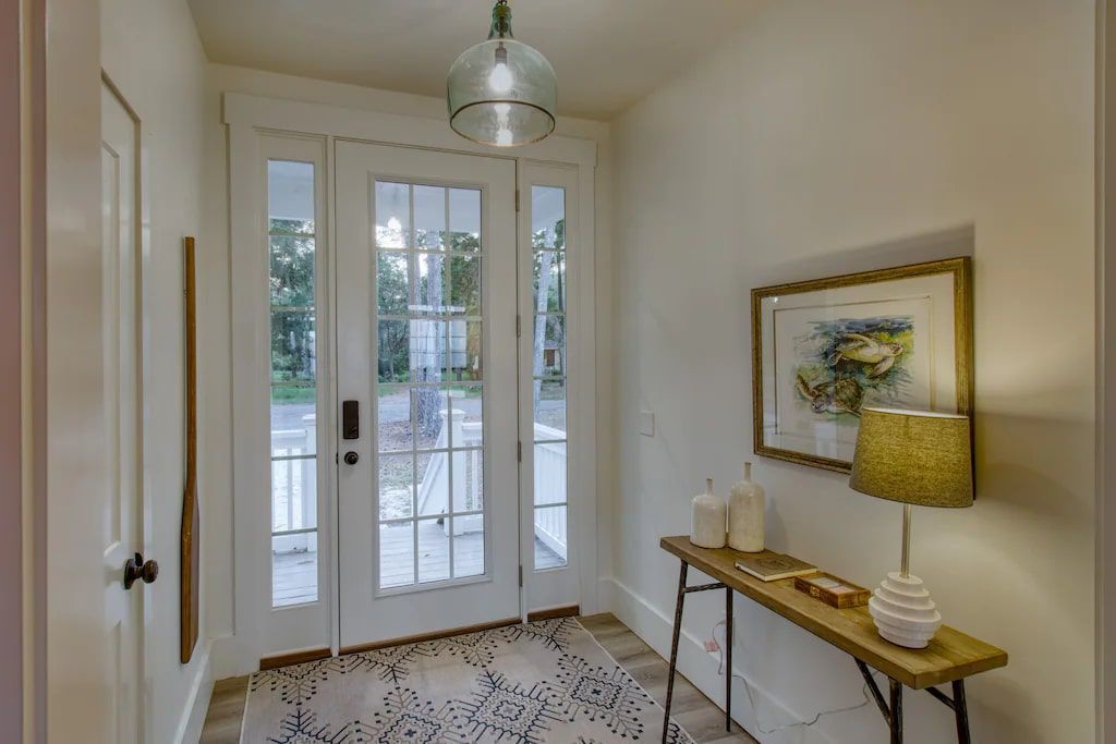 A hallway with a table and a lamp in front of a door.