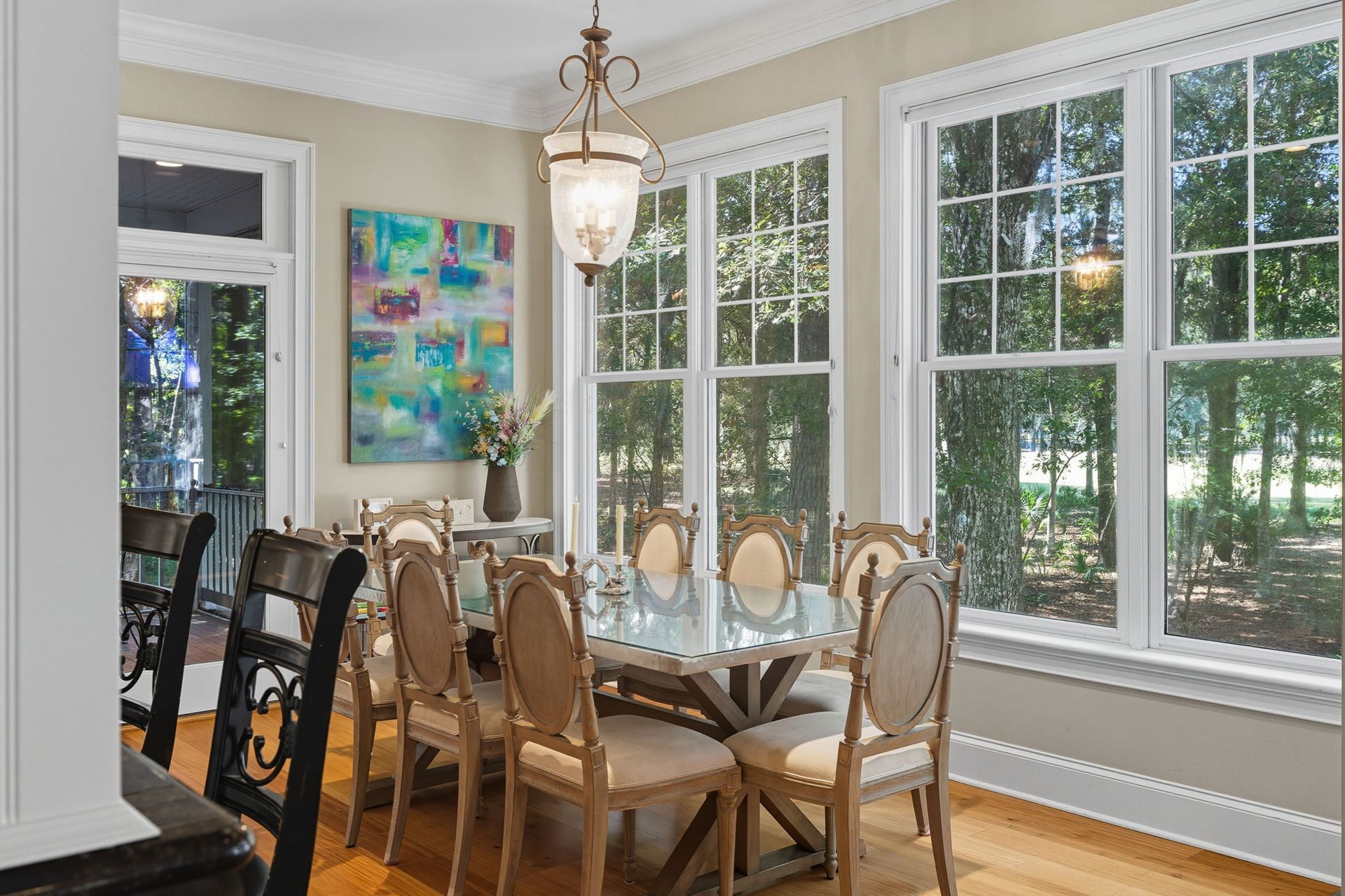 A screened in porch with a table and chairs and a view of the ocean.