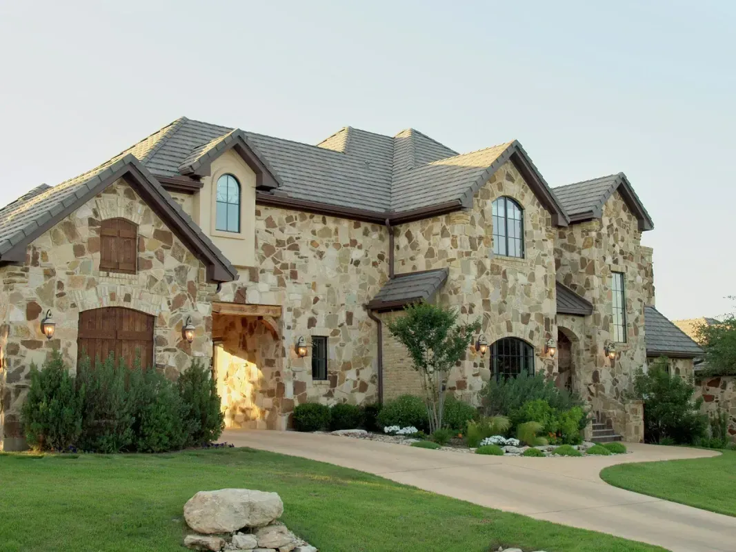 A large stone house with a driveway leading to it