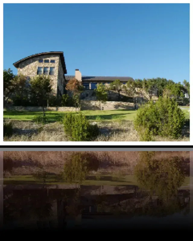 A large house sits on top of a hill next to a body of water