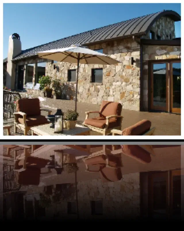 A stone house with a patio area with chairs and umbrellas