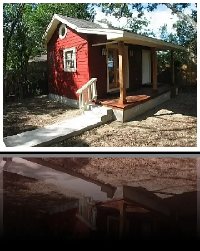 A small red house with a porch and stairs