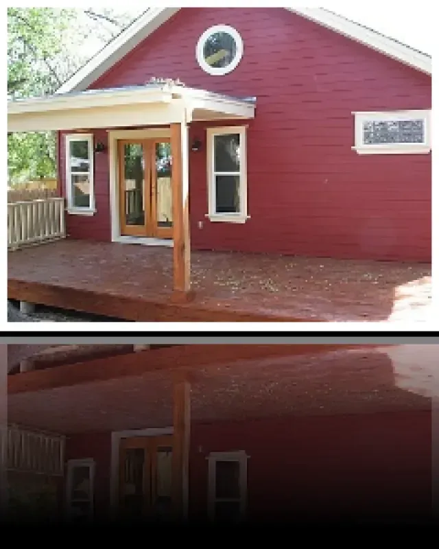 A red house with a wooden deck and a round window