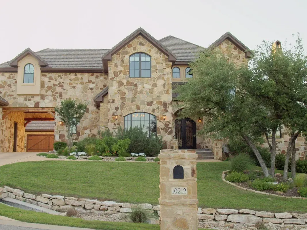 A large stone house with a mailbox in front of it
