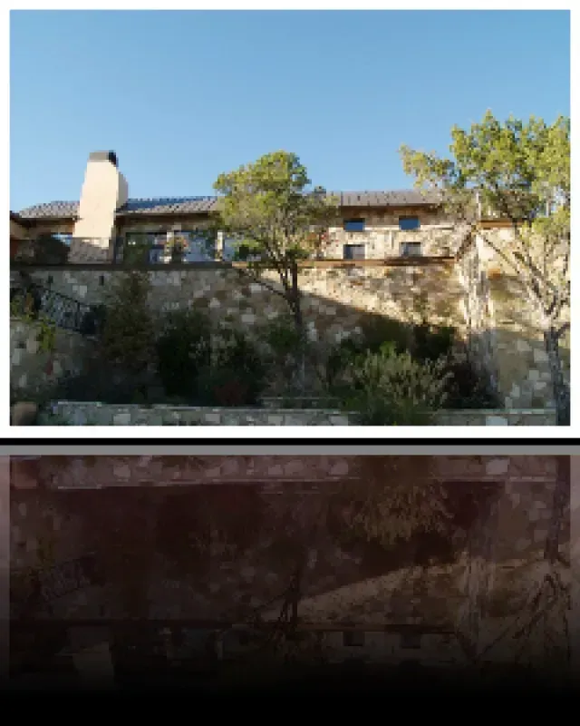 A large house sits on top of a hill surrounded by trees