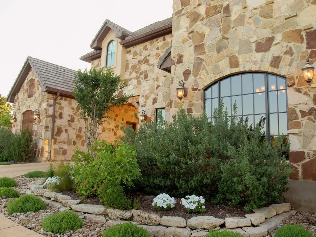 A large stone house with a garden in front of it