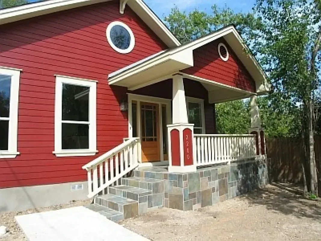 A red house with a porch and stairs