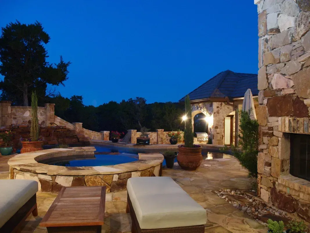 A patio with a hot tub and chairs at night