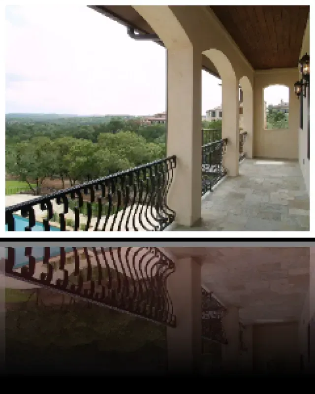 A balcony with a wrought iron railing overlooking a forest