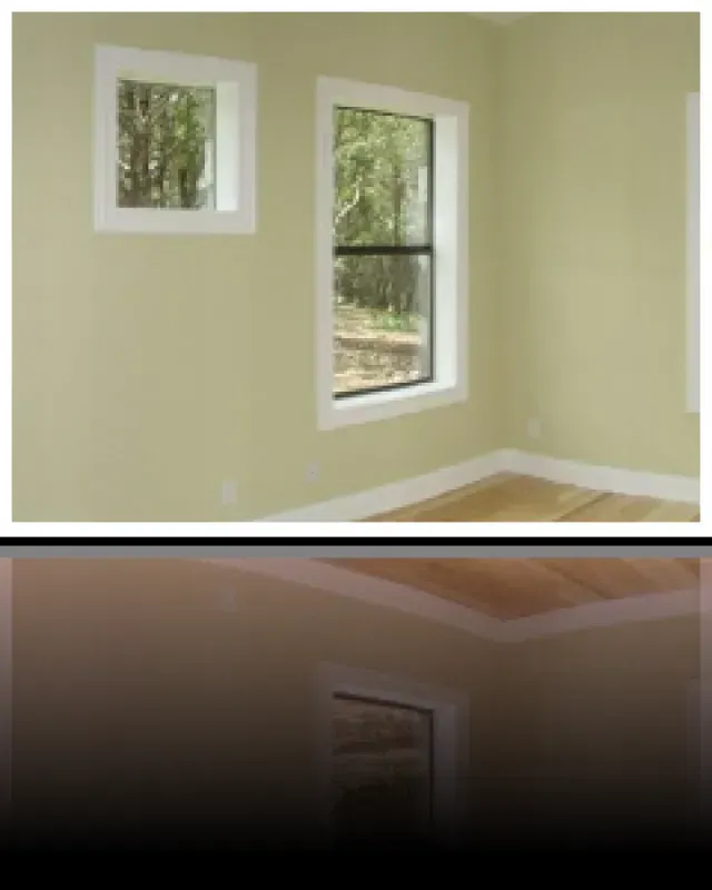 An empty room with two windows and a wooden floor