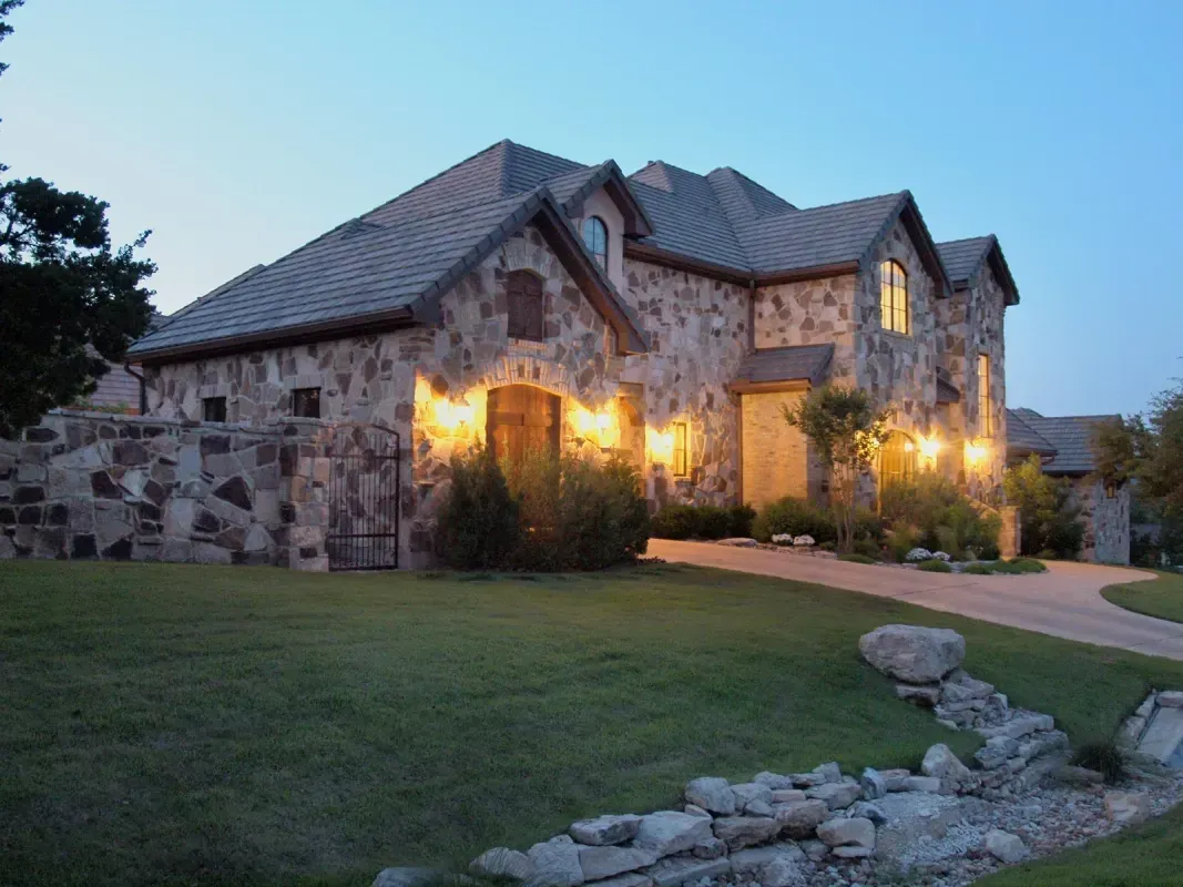 A large stone house with lights on in the evening