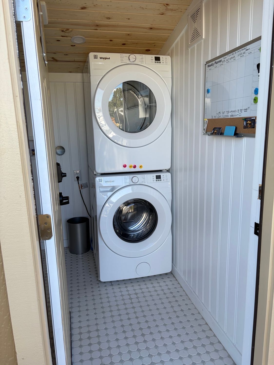 Laundry machines in a narrow utility room with white walls and a tiled floor