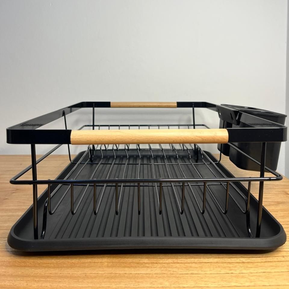 Un escurreplatos negro con mango de madera está sobre una mesa de madera.
